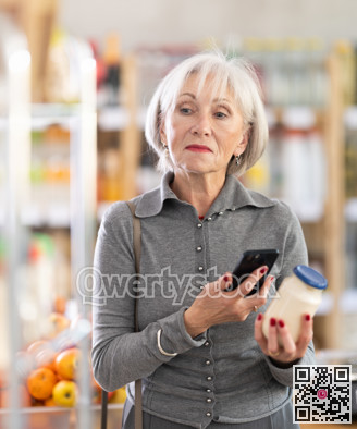 Elderly female shopper scanning QR code on bottle mayonnaise label in grocery department of supermarket