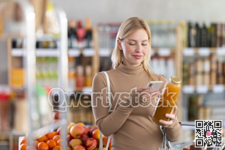Girl scan QR code, take reading peach juice label using phone camera in shop
