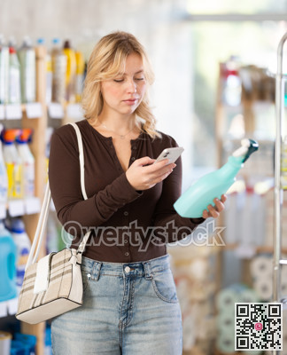Before making purchase, girl buyer scan QR code on packaging of glass cleaner spray