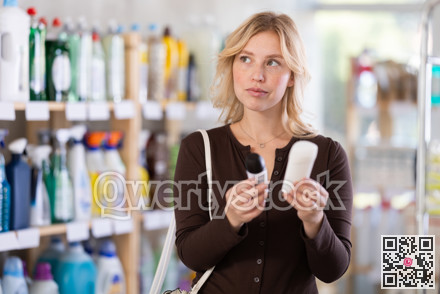 Girl housewife in household store examines goods, chooses roll-on deodorant