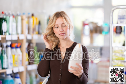 Girl housewife in household store examines goods, chooses hair care product