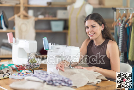 Female clothing designer stitching fabric on sewing machine in studio
