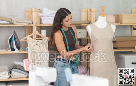 Fashion designer fitting dress on mannequin in dressmaker studio
