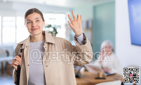 Adult woman leaving office saying goodbye to colleague