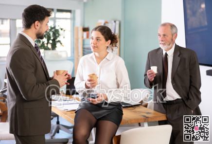 Girl with two men colleagues chat and laugh during coffee break