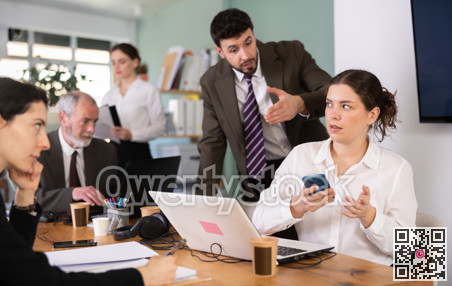 Strict male boss scolding female office worker for scrolling social media on smartphone during work hours in office of business company
