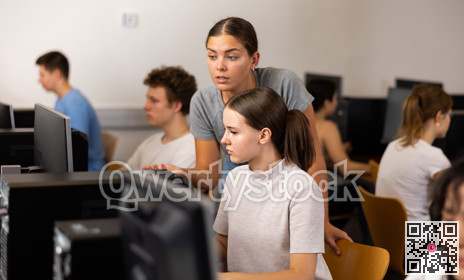 Focused female student explaining the topic to female friend while she is studying computer science on the pc in the classroom
