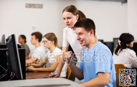 Smiling teenagers using computer during computer science lesson