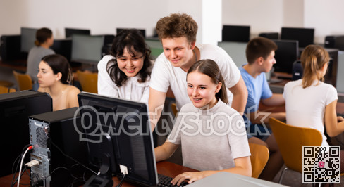 Portrait of multinational young students group emotionally reacting while studying at pc in computer class