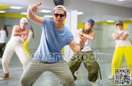 Emotional teen boy dancing with group of friends in dance studio. Hip hop generation