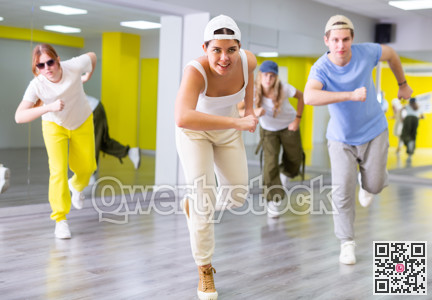 Happy heenagers in dance hall studying new movements, smiling and having fun