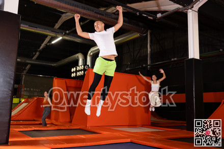 Emotional man jumping vertical and flying in trampoline sport center indoors