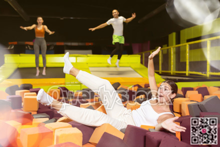 Happy girl diving into foam cube pit at indoor trampoline park