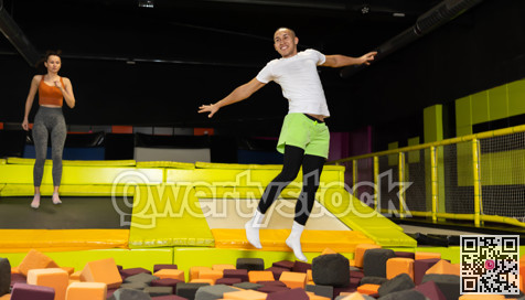 Joyful guy jumping into foam pit at indoor trampoline arena