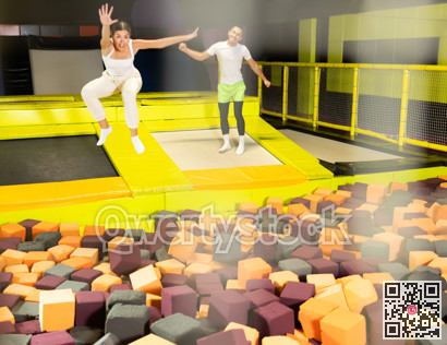 Joyful girl jumping into foam pit at indoor trampoline arena