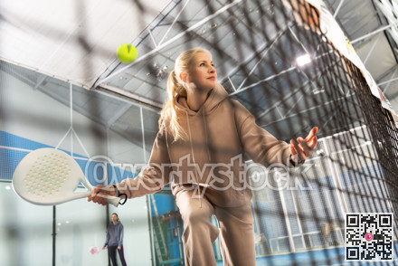 Sportive woman playing padel together with a partner. View through tennis net