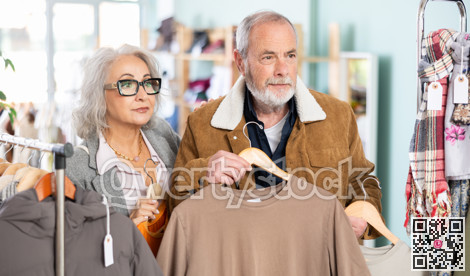 Mature married couple chooses fashionable t-shirt in clothing store