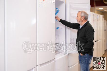 Elderly man chooses refrigerator in appliance store