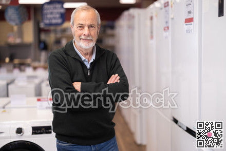 Elderly man choose modern fridge at supermarket