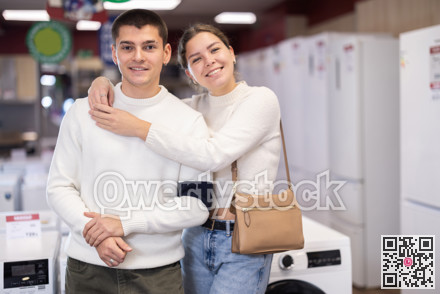 Young couple chooses modern washing machine or dishwasher at hypermarket