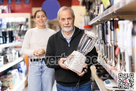 Young woman with elderly man choosing blender in store
