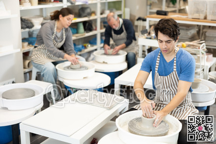 Young man shaping pottery on wheel in ceramics studio