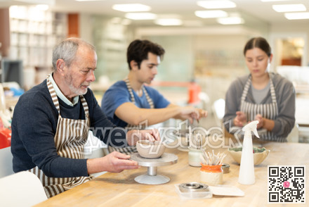 Eldery man sculpts ceramic piece in workshop