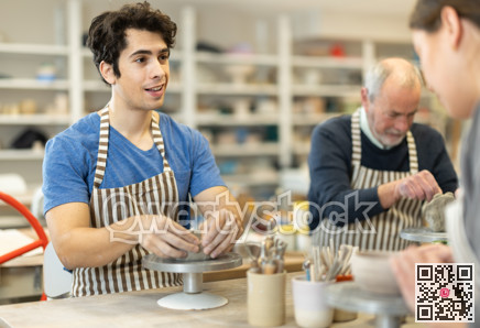 Man at table molds cup from wet clay in pottery workshop