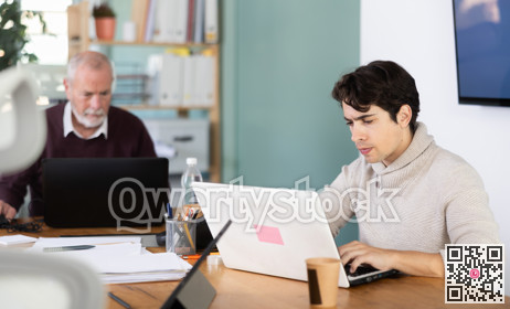 Elderly and young men working in office