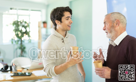 Young and elderly men colleagues drinking coffee in office