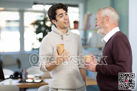 Young and elderly men colleagues drinking coffee in office