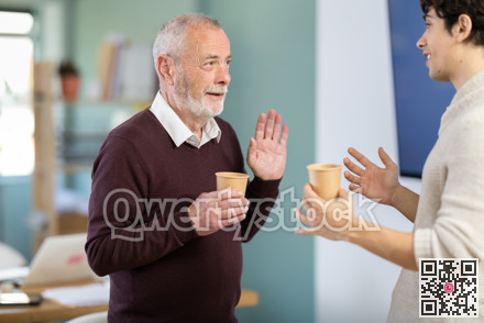 Two office workers drink coffee and chat during work break