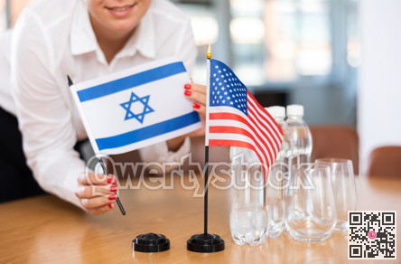 Flags of Israel and USA stand on negotiating table in office