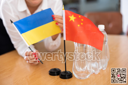 Unrecognizable girl sets midget flags of China and Ukraine before international negotiations
