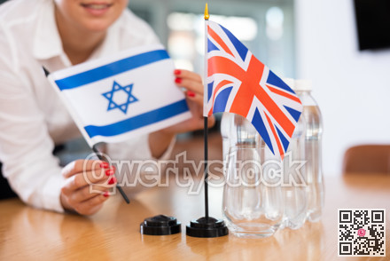Office coordinator setting flags of Israel and United Kingdom on table