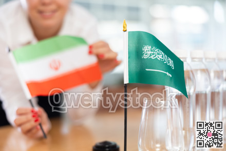 Unrecognizable girl sets midget flags of Saudi Arabia and Iran before international negotiations