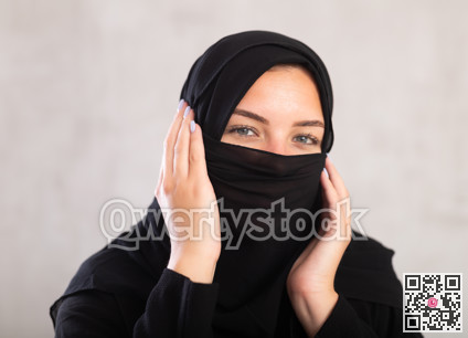 Muslim woman with face covered with burka holds thin fabric of yashmak with her hands