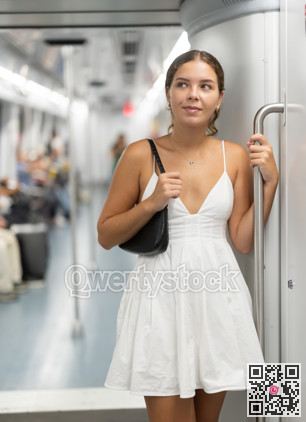 Young woman in dress standing in subway car