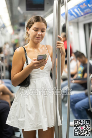 Positive young girl standing on wagon holding phone in hand