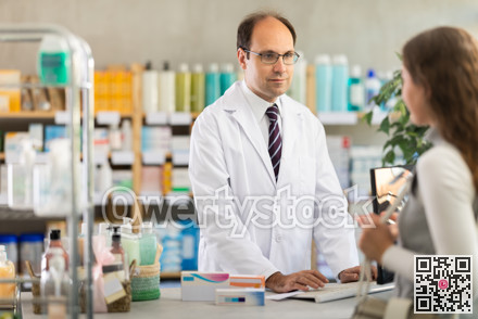 Pharmacist searches for medicine on computer for female buyer