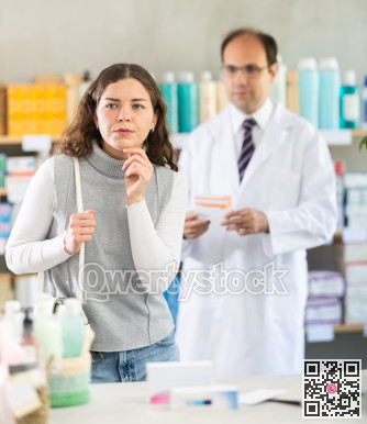 Female customer chooses medicines in drugstore. Pharmacist helps her