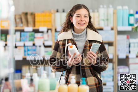 Girl in winter clothes choosing skin cream at drugstore