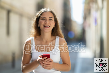 Young woman checking phone while walking in summer city