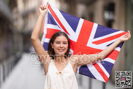 Cheerful girl holding national flag of UK flag, standing outdoors