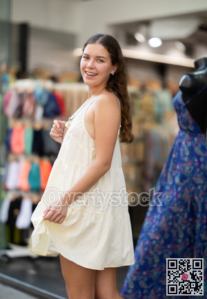 Young girl in white dress is looking for something at street market - looking at goods with interest