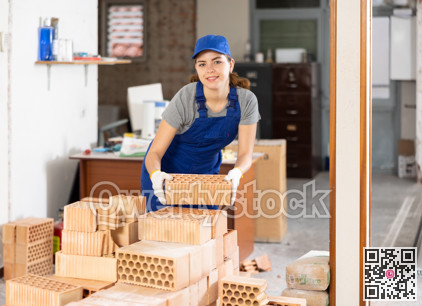 Female builder stacking bricks at construction site