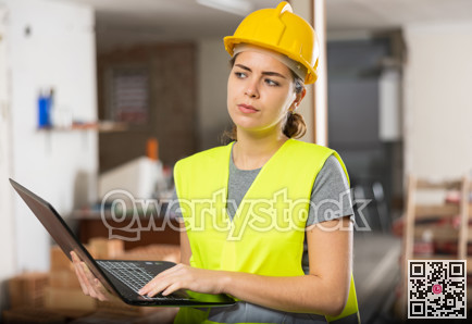 Woman with laptop on indoor construction site