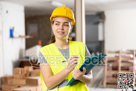 Smiling female civil engineer standing with papers at construction site