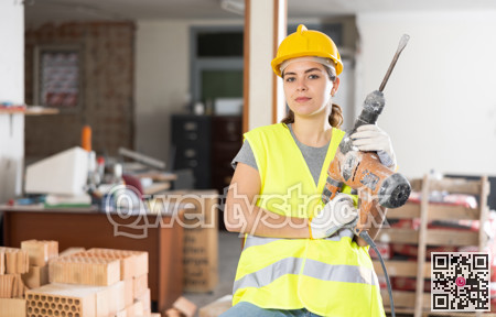 Portrait of positive woman builder standing in construction site