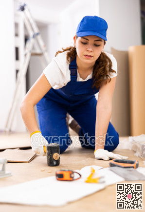 Woman builder puts laminate on the floor in room